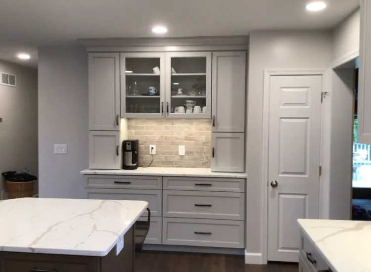 A spacious and bright kitchen with white cabinetry, modern appliances, and a large center island perfect for casual dining and entertaining. The natural stone backsplash adds a touch of rustic charm.
