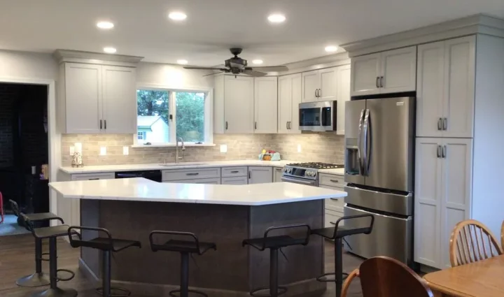 A sleek and modern kitchen outfitted with light gray cabinetry, a large center island with bar stools, and state-of-the-art appliances, making it ideal for both cooking and entertaining.