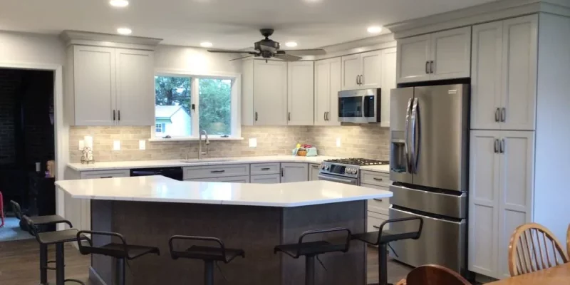 A sleek and modern kitchen outfitted with light gray cabinetry, a large center island with bar stools, and state-of-the-art appliances, making it ideal for both cooking and entertaining.